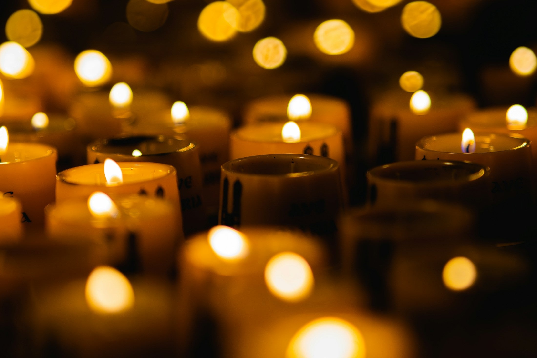 Rows of lit votive candles glowing in a dark church