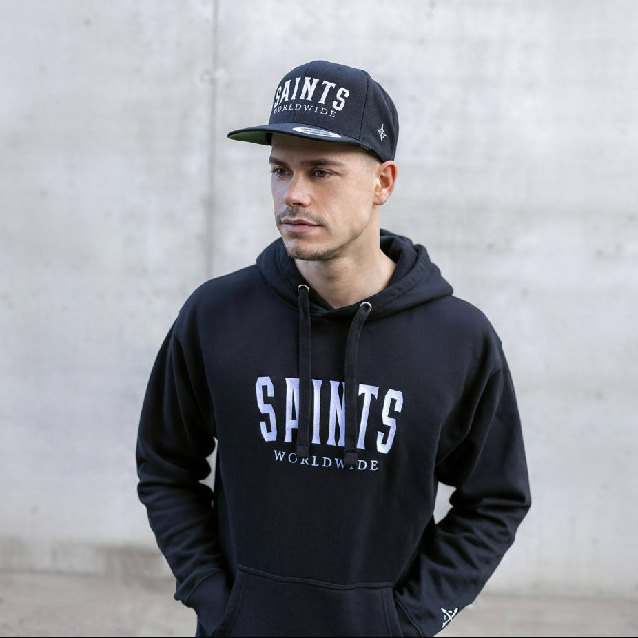 Model wearing full Saints Worldwide outfit, featuring hoodie and black embroidered snapback