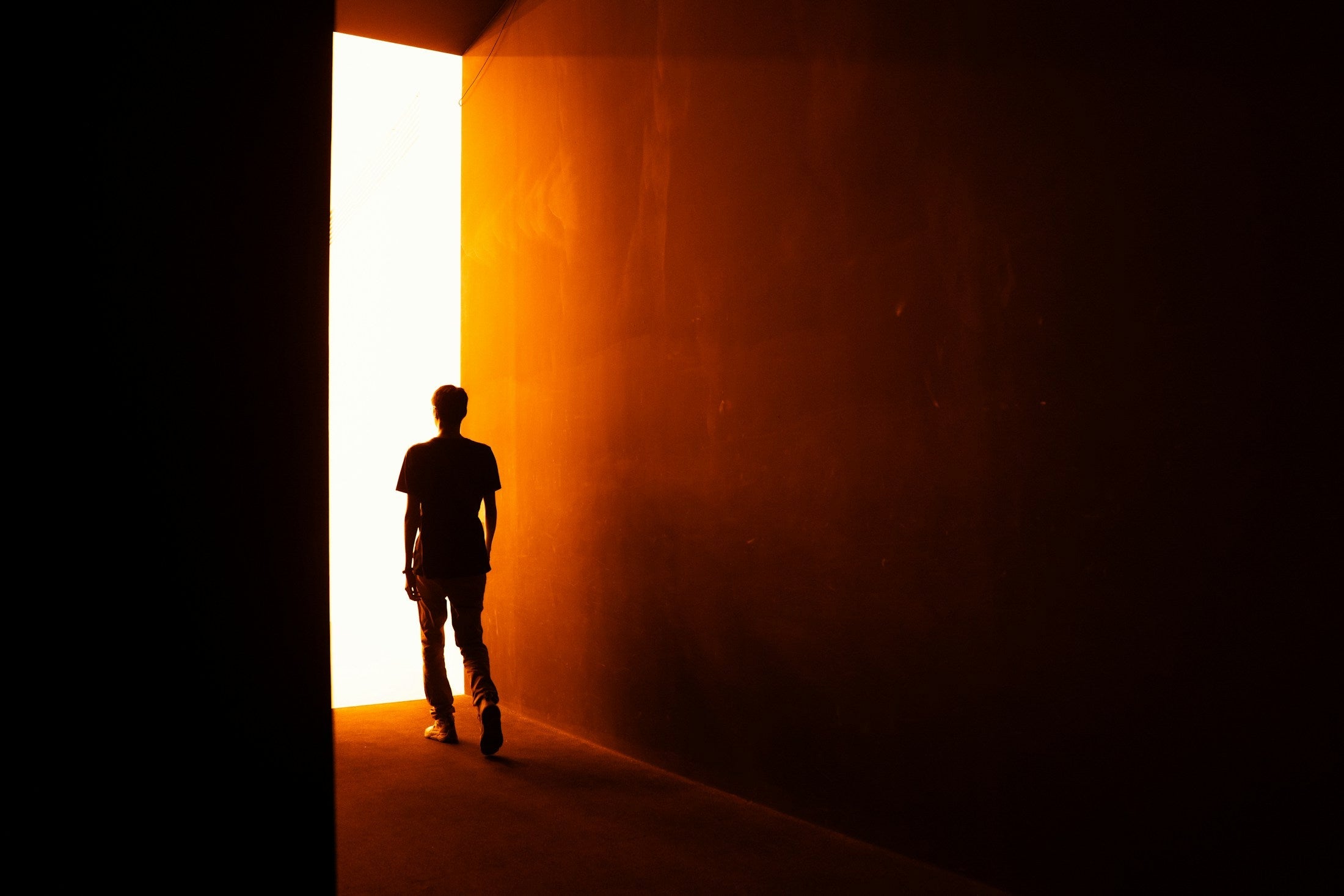 Person walking through darkness toward a bright light ahead